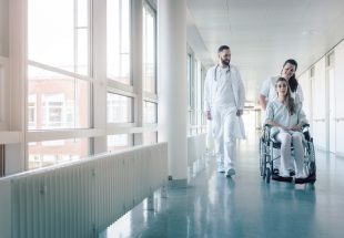 Médecin, infirmière et une patiente en fauteuil roulant dans les couloirs d'un hôpital