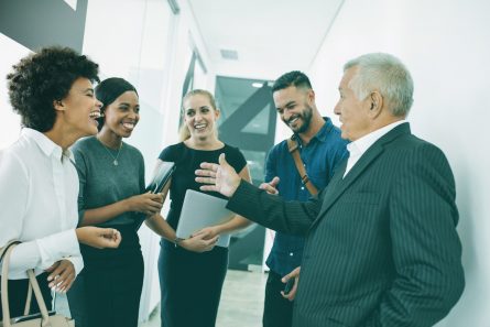 Un manager et son équipe rient dans un couloir