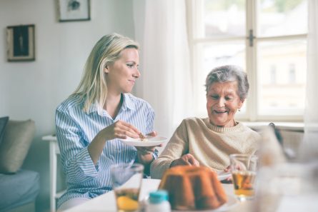 Une dame âgée en fauteuil reçoit de la visite pour le goûter