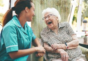 Une dame âgée rit aux éclats auprès d'une infirmière